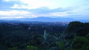 Une vue panoramique d’une ville, avec des montagnes en arrière-plan, le tout entouré d’une végétation luxuriante.