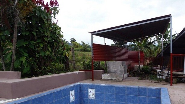 Une piscine aux carreaux bleus, un espace détente abrité et une structure en béton.