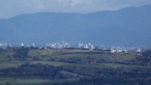 Un paysage urbain avec une chaîne de montagnes en arrière-plan, comprenant un mélange de bâtiments résidentiels et commerciaux.
