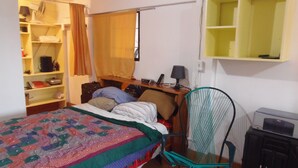 Une chambre à coucher comprenant un lit, un bureau, une chaise, une armoire et une étagère.