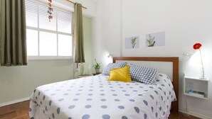 A bedroom with a bed, curtains, a nightstand, and wall art.