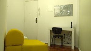 A small room with a yellow chair, a desk, and a white door.