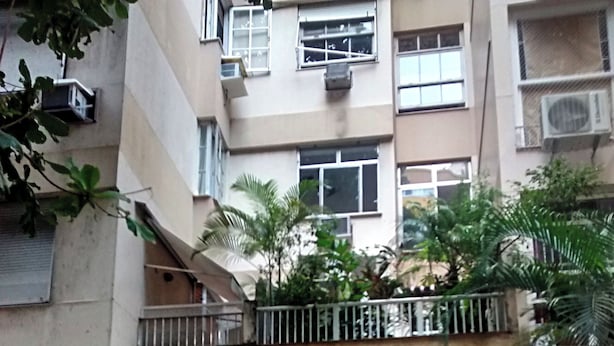 A gated entrance to a residential building with a balcony and air conditioning units.