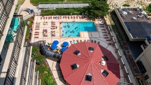 Vista aérea de un hotel con piscina, tumbonas y una zona de estar cubierta.