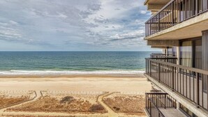 Un hotel frente a la playa con varios balcones con vistas al océano.
