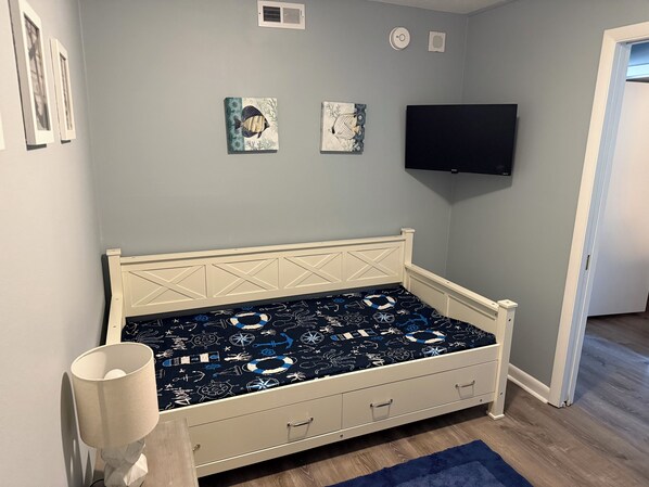 A bedroom with a bed, a TV, and a door.