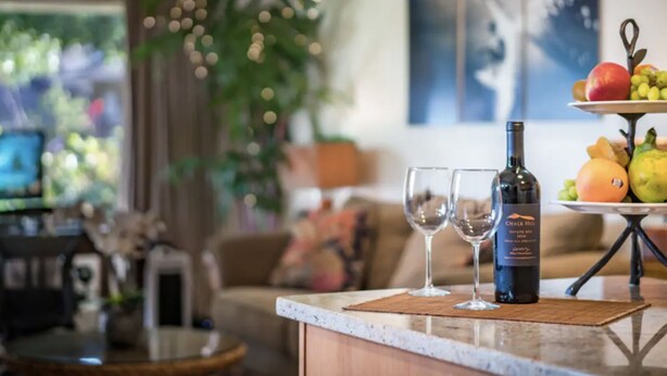 A bar area with a wine bottle, two glasses, and a fruit display. - Private Guest Suite near Beaches, Hiking & Golfing (Princeville)