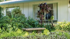 A house with a garden in front, a bench, and a window with curtains. - Private Guest Suite near Beaches, Hiking & Golfing (Princeville)
