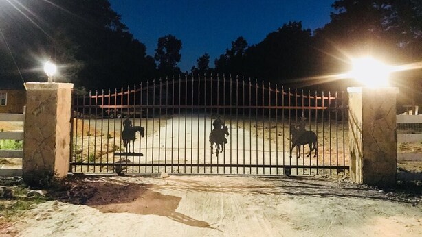 A gated area with three horses, a dirt ground, and a fence.
