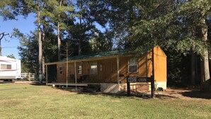 A small wooden cabin labeled 'CEDAR CABIN' with a porch and a covered outdoor seating area.