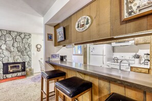 Cozy kitchen with fireplace, bar counter, and essential appliances.