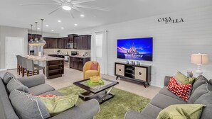 A modern living room with a grey sofa, a coffee table, and a TV displaying a Disney movie.