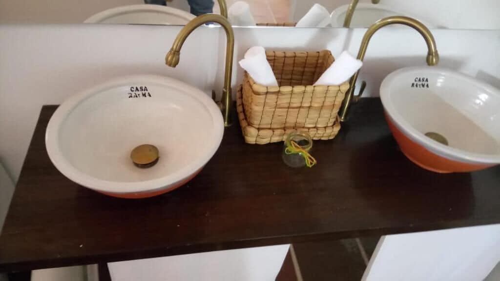 A bathroom with two sinks, each labeled 'CASA 2Ar M4'. There is a woven basket with towels and a small bottle.