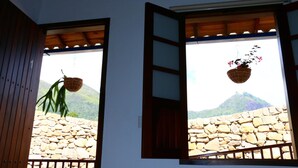 Two windows with wooden frames and open shutters, each with a hanging plant. - Casa Rayma Hotel Boutique (Contratación)
