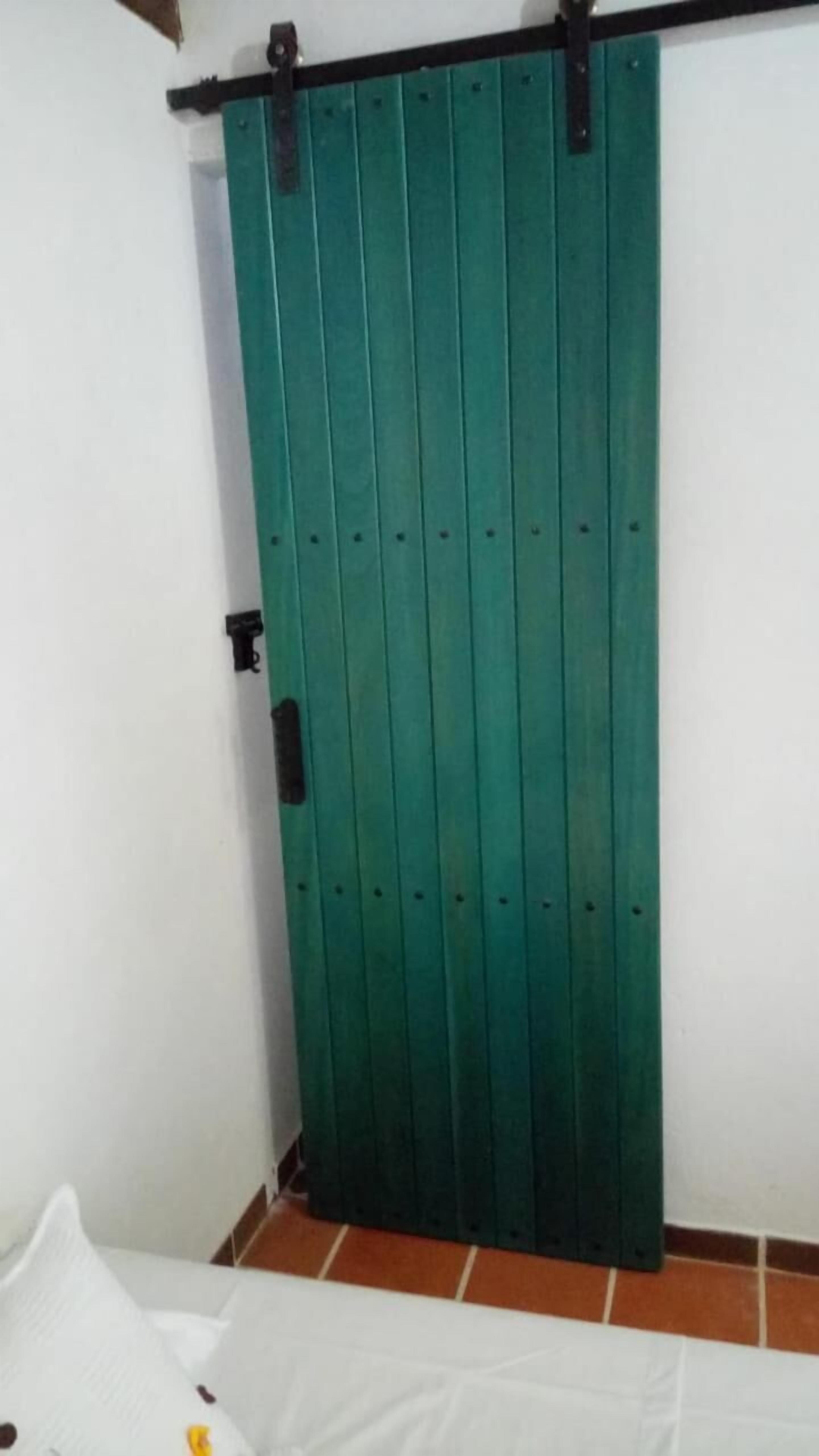 A room with a green sliding door, white walls, and a tiled floor.