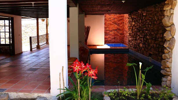 A covered outdoor area with a pool table, a stone wall, and a tiled floor. - Casa Rayma Hotel Boutique (Contratación)