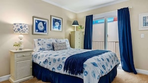 A bedroom with a bed, bedside tables, a lamp, and artwork on the walls.