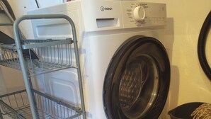 A front-loading washing machine with a metal shelf unit beside it. - Apartment, with pool, near the beach (Albufeira)