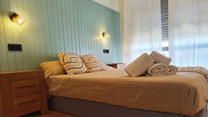 A neatly made bed with a striped bedspread, two decorative pillows, and rolled towels on a wooden nightstand. - Apartment, with pool, near the beach (Albufeira)