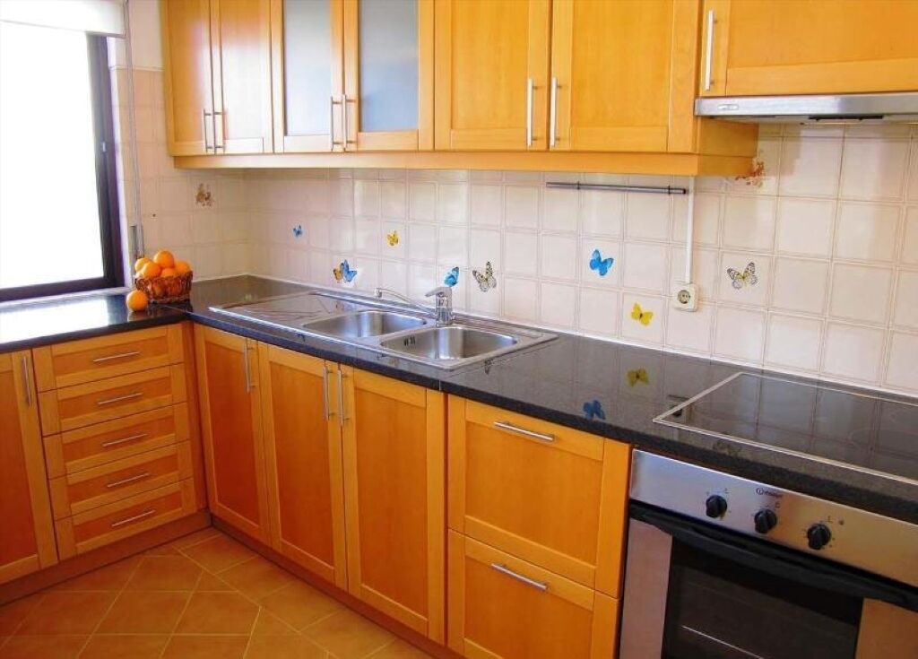 A kitchen with wooden cabinets, a double sink, and a stove.