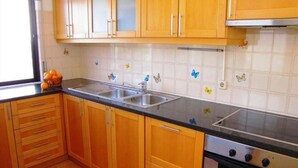 A kitchen with wooden cabinets, a double sink, and a stove. - Apartment, with pool, near the beach (Albufeira)