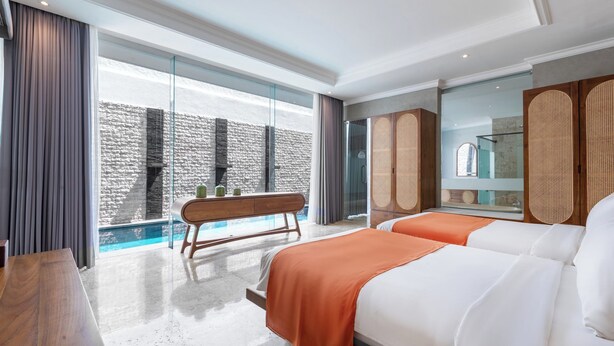 Una habitación de hotel moderna con un ventanal grande, un banco de madera, dos camas y una mesita.