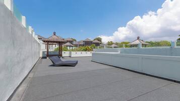 Une terrasse sur le toit, dotée de chaises longues, d’une pergola et offrant une vue sur la mer.