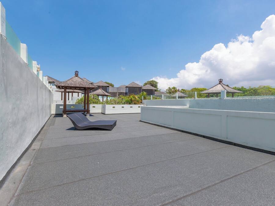 Une terrasse sur le toit, dotée de chaises longues, d’une pergola et offrant une vue sur la mer.