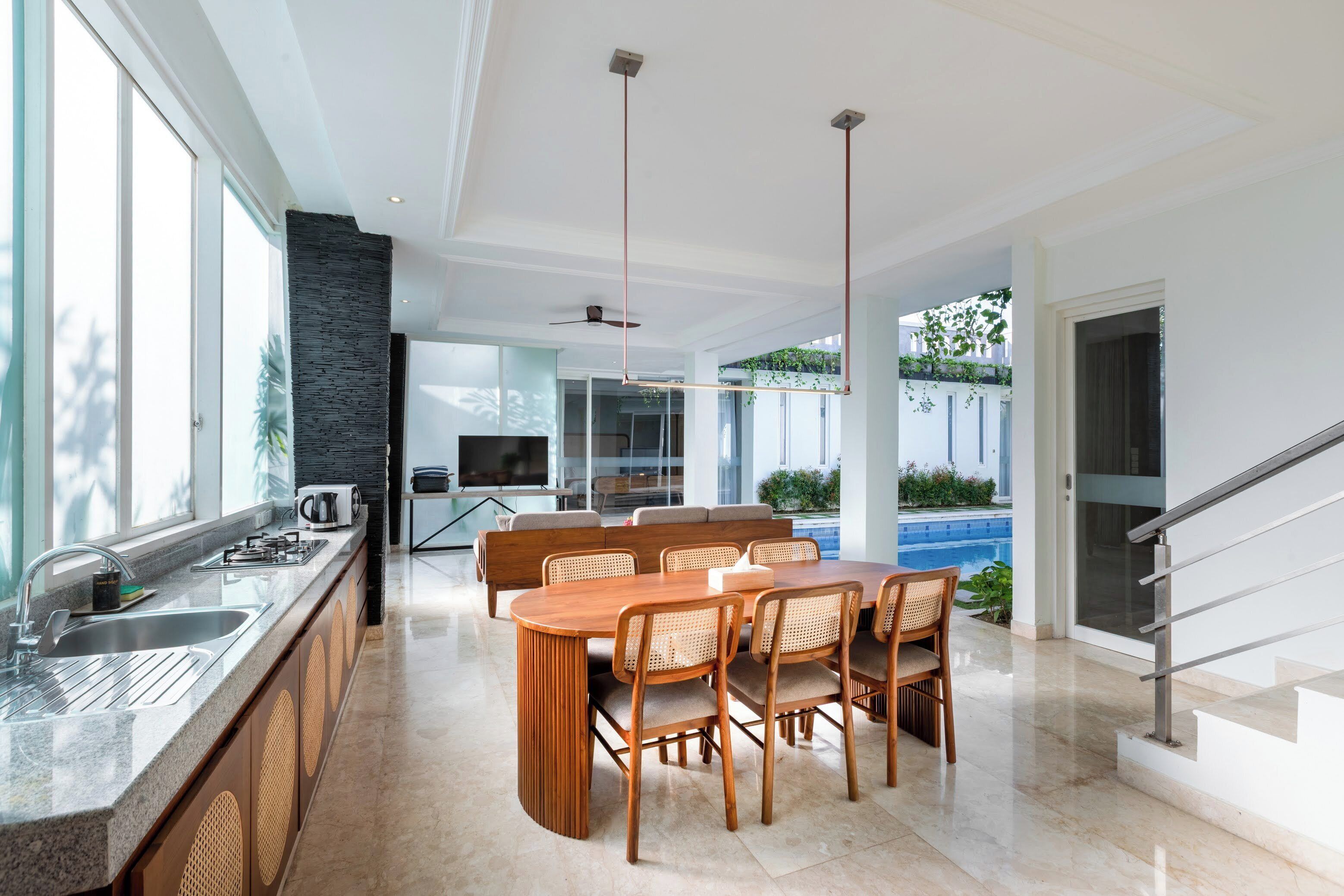 A modern kitchen with a dining area, large windows, and a pool view.