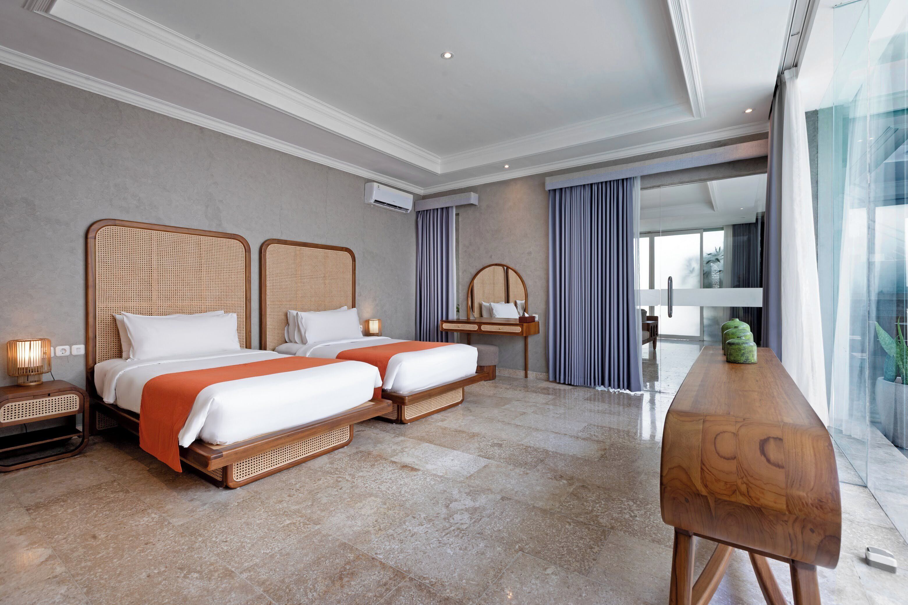 Habitación de hotel con dos camas, una mesa de madera, un espejo y vistas al exterior.