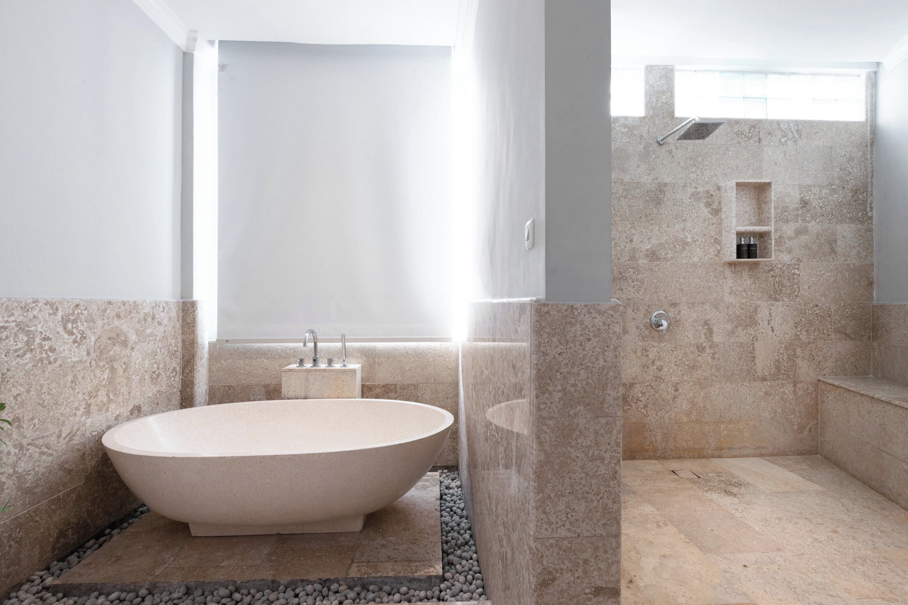 Een moderne badkamer met een vrijstaand bad, een douchegedeelte en een klein plankje met toiletartikelen.