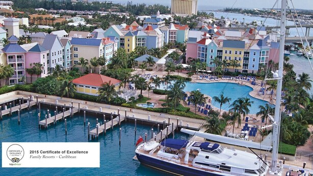 Un complexe hôtelier avec des bâtiments aux couleurs vives, un port de plaisance et un grand yacht.