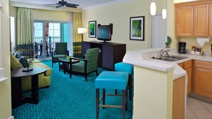 Une chambre d’hôtel dotée d’un coin salon, d’une kitchenette et d’un balcon.