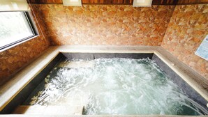 A hot tub with flowing water, surrounded by stone tiles and wooden paneling. - Sol Y Viento Hotel and Resort (Calamba)