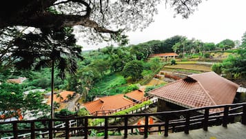 A traditional building with a tiled roof, surrounded by lush greenery and a wooden fence.