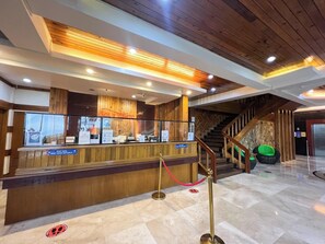 Una zona de recepción con mostrador de madera, una escalera y una vitrina de vidrio.