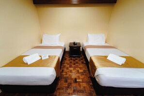 A hotel room with two single beds, a wooden parquet floor, and a small bedside table with a lamp. - Sol Y Viento Hotel and Resort (Calamba)