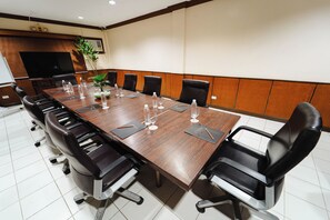 A conference room with a long wooden table, black leather chairs, and a large flat-screen TV. - Sol Y Viento Hotel and Resort (Calamba)
