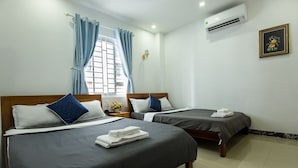 Ein Hotelzimmer mit zwei Betten, einem Fenster mit Vorhängen, einer Klimaanlage und einem gerahmten Bild an der Wand.