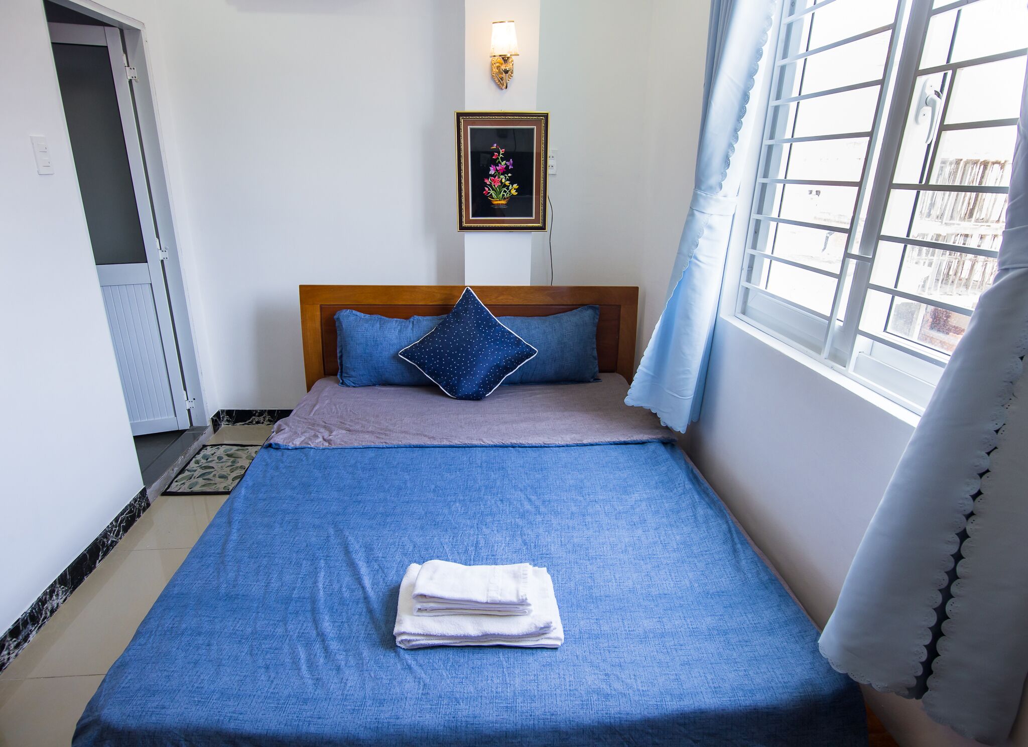 A neatly made bed with blue bedding, a pillow, and a folded towel.