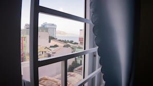 Blick aus einem Fenster mit Metallrahmen und einem Ziervorhang.