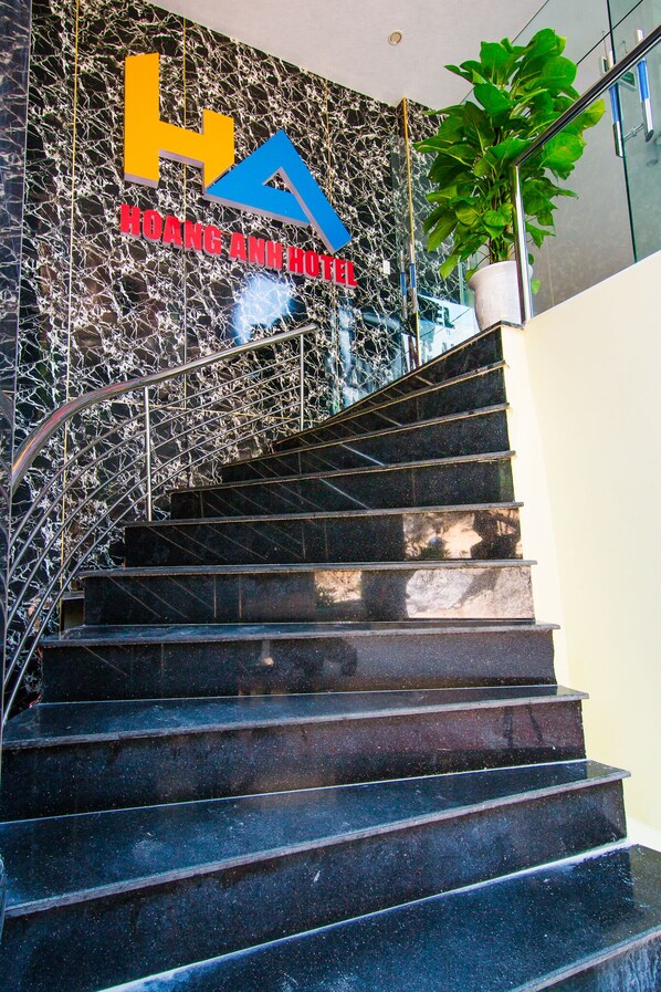 A staircase with a marble wall and a sign for Hoang Anh Hotel.