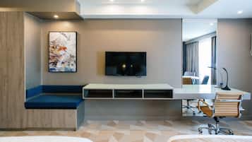 Une chambre d’hôtel moderne, dotée d’un grand lit, d’un bureau avec une chaise, d’une télévision et d’un tableau au mur.