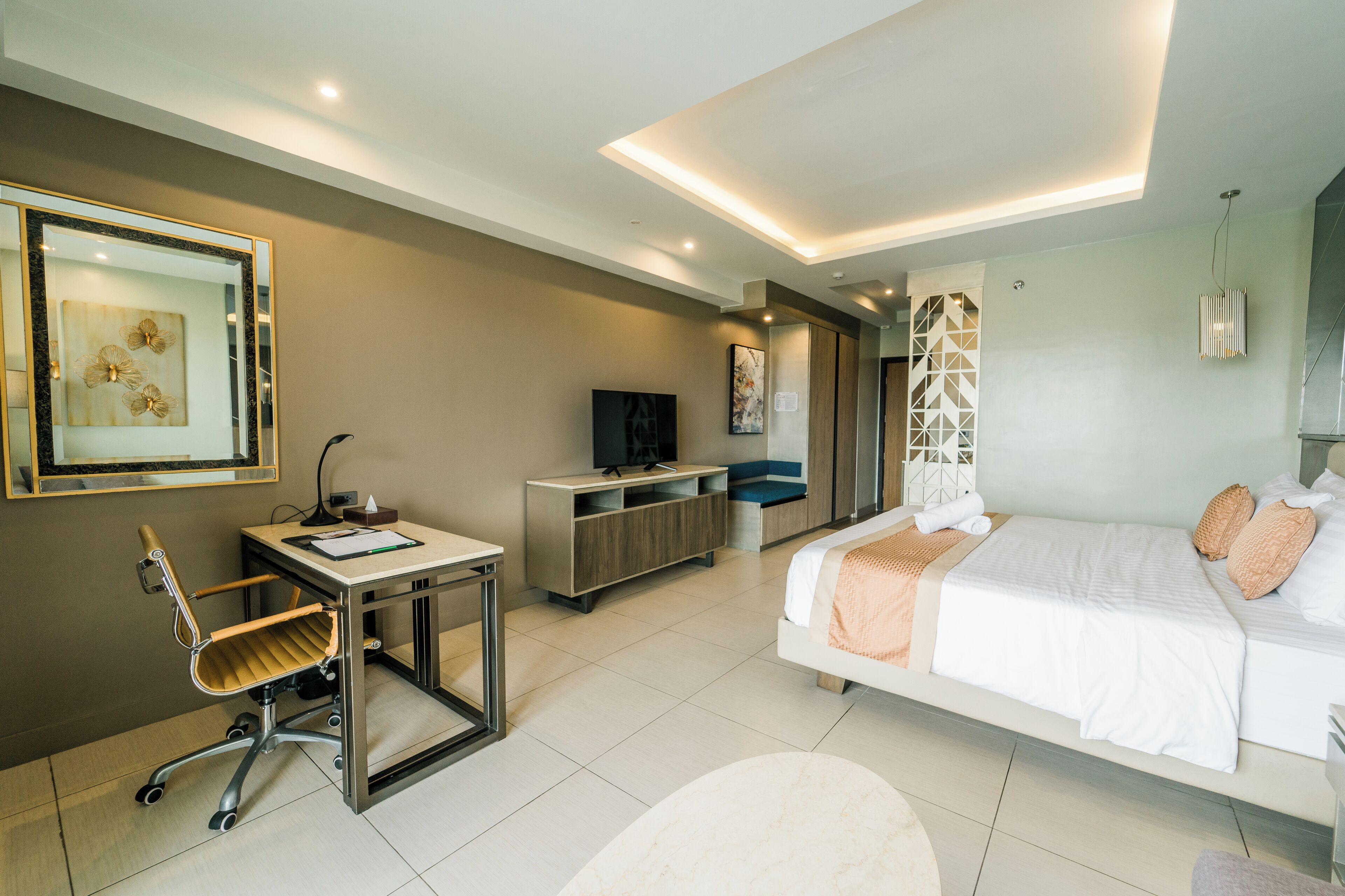 Een moderne hotelkamer met een bed, bureau, stoel, televisie en kunstwerk.