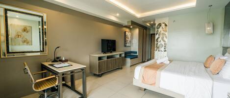 Una habitación de hotel moderna con cama, escritorio, silla, televisión y obras de arte.