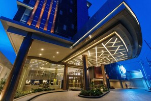 A modern hotel entrance with a curved facade, large glass windows, and a prominent sign. - Zuri Hotel (Iloilo)