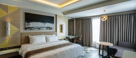 Habitación de hotel moderna con una cama grande, un escritorio, una silla y vistas al exterior.