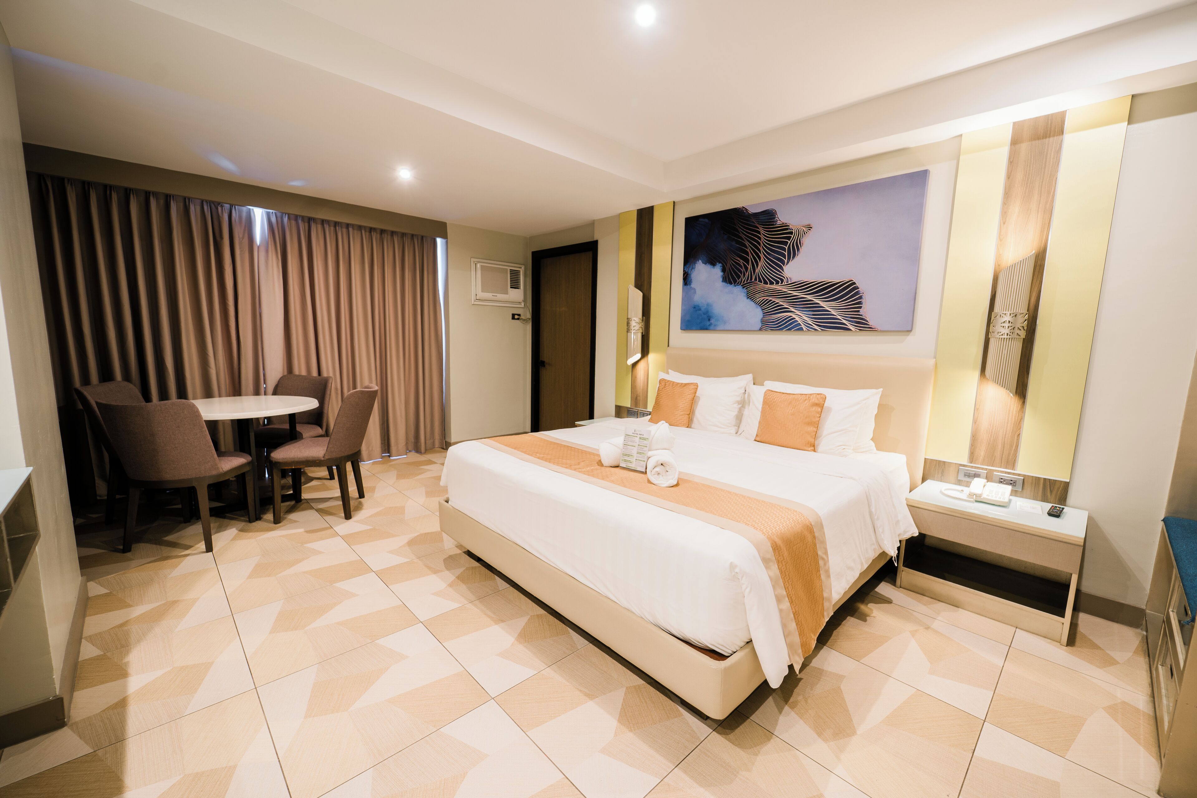A hotel room with a large bed, a desk, and a chair.