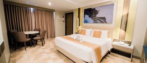 A hotel room with a large bed, a desk, and a chair.