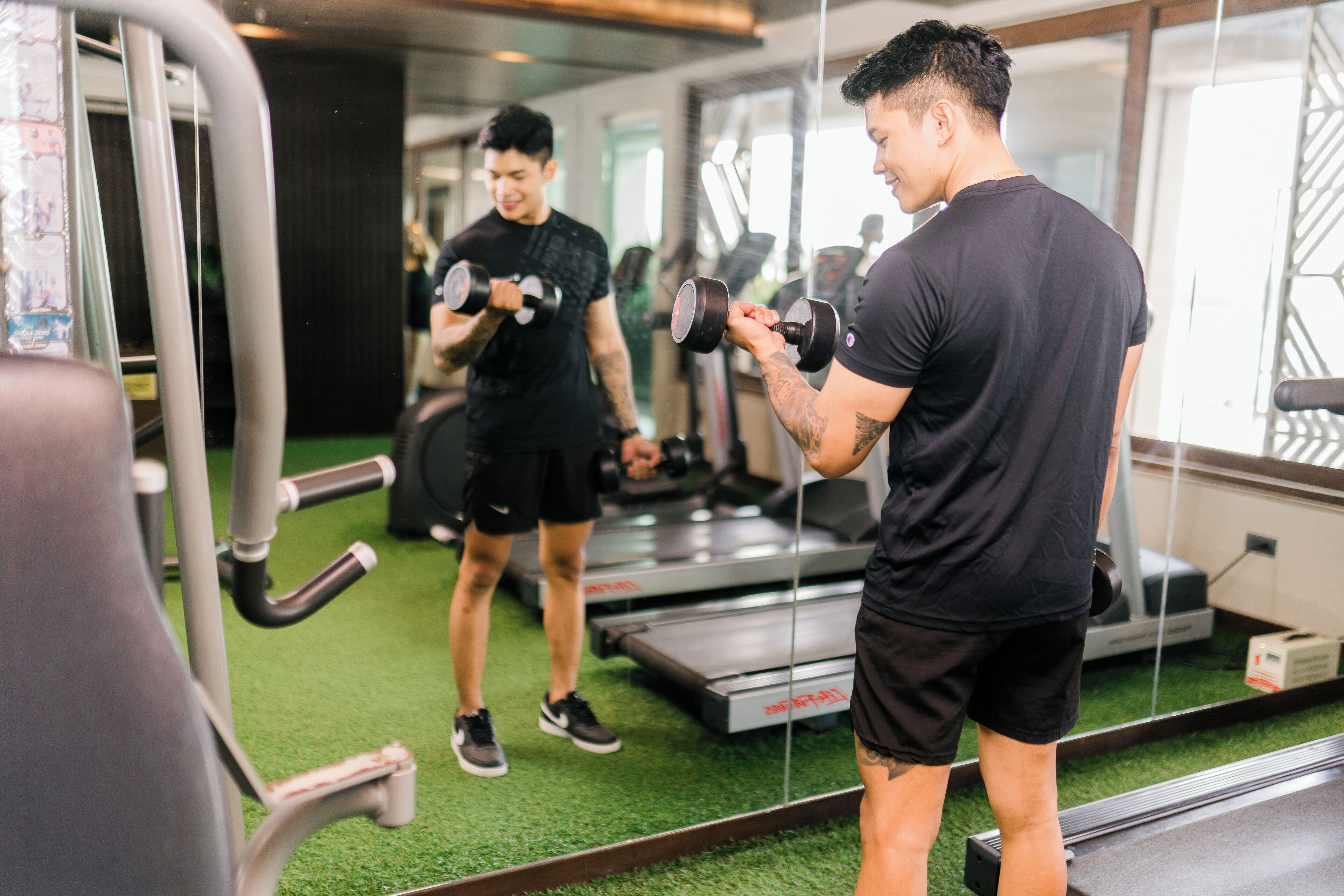 Ein Fitnessraum mit Laufbändern, Gewichten und einem Spiegel.